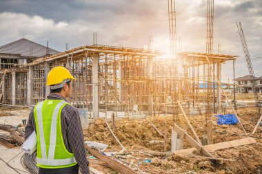 Asyalı işadamı inşaat mühendisi koruyucu miğfer ve bina inşaatında kullanılacak planlar.