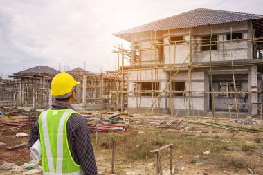 Asyalı işadamı inşaat mühendisi koruyucu miğfer ve bina inşaatında kullanılacak planlar.