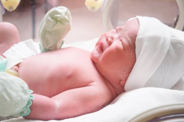 Yeni doğmuş bebek hastanedeki kuvözde uyuyor.