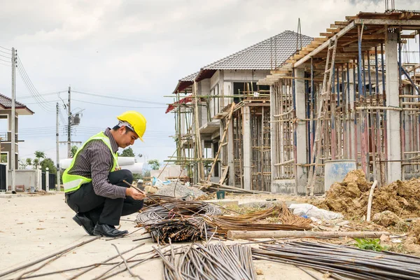 亚洲商人 建筑工程师 戴着防护头盔 手头上拿蓝图纸 望着房屋建筑工地的钢筋 — 图库照片