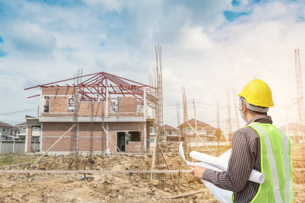 İnşaat alanının arka planında koruyucu mimar ve bina planları olan profesyonel mühendis.