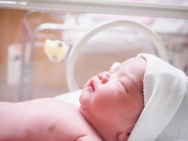Newborn baby girl inside incubator in hospital post delivery room