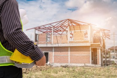 Asyalı işadamı inşaat mühendisi koruyucu miğfer ve bina inşaatında kullanılacak planlar.