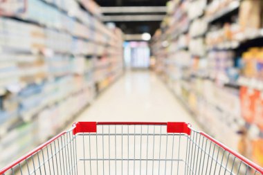Soyut bulanık süpermarket indirim mağazası koridoru ve ürün rafları olan boş alışveriş arabası.