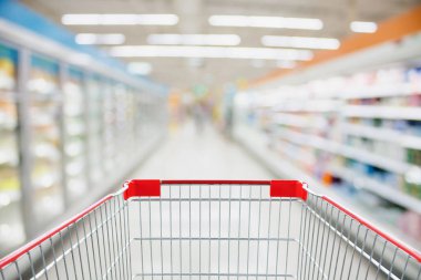 Süpermarket koridoru boş kırmızı alışveriş arabasıyla bulanık arka plan