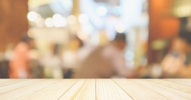Boş ahşap masa üstü, restoran kafesi ya da müşteri bulanıklığı olan kahve dükkânı içi montaj ürün görüntüleme arka planı için soyut vintage stil bokeh ışığı