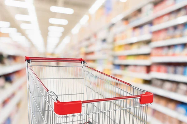 スーパーマーケットの通路を背景に空の赤いショッピングカート — ストック写真