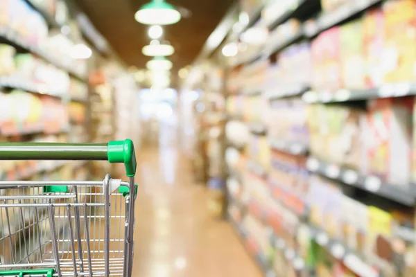 Empty green supermarket shopping cart with abstract blur grocery store aisle defocused background