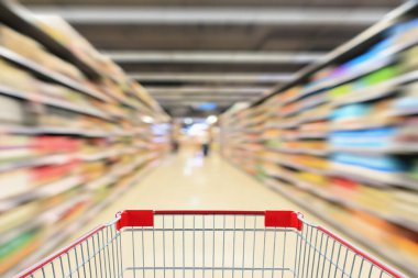 Süpermarket koridorundaki alışveriş arabasının içinde ürün rafları iç odaklanmış bulanık arkaplan