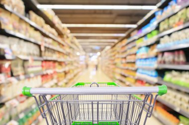 Süpermarket koridorundaki alışveriş arabasının içinde ürün rafları iç odaklanmış bulanık arkaplan