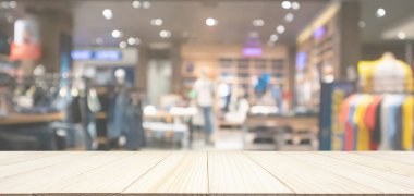 Modern alışveriş merkezindeki soyut bulanık giyim mağazası olan boş ahşap masa kapağı kapatılmış arka plan