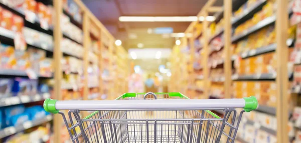 Süpermarket koridorundaki alışveriş arabasının içinde ürün rafları iç odaklanmış bulanık arkaplan