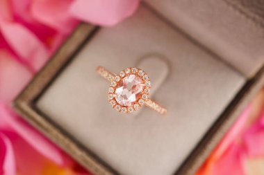 Güzel pembe gül yapraklı arka planda mücevher kutusunda zarif bir nikah yüzüğü.