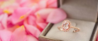Güzel pembe gül yapraklı arka planda mücevher kutusunda zarif bir nikah yüzüğü.