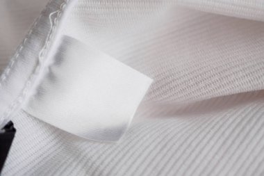 Pamuk gömlek arka planında beyaz boş giyim etiketi