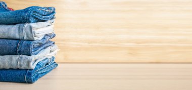 Ahşap arka planda kot pantolon yığını