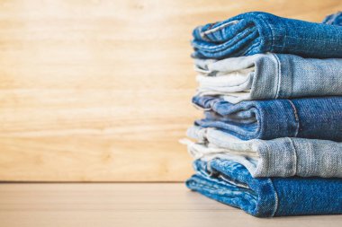 Ahşap arka planda kot pantolon yığını