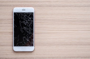 Ahşap arka planda kırılmış cep telefonu ekranı
