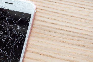 Ahşap arka planda kırılmış cep telefonu ekranı