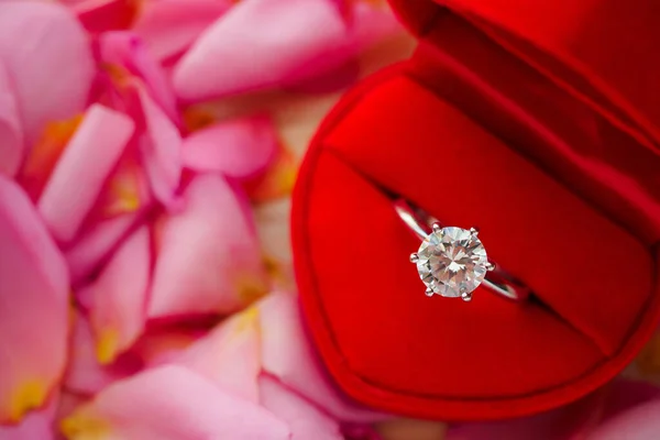 美しいピンクのバラの花びらの背景の上の赤いハートジュエリーボックスのエレガントな結婚指輪 — ストック写真