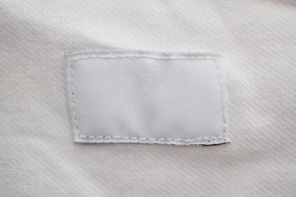 Pamuk gömlek arka planında beyaz boş giyim etiketi