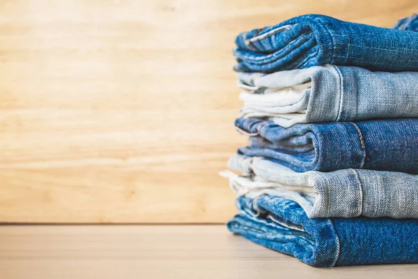 Ahşap arka planda kot pantolon yığını