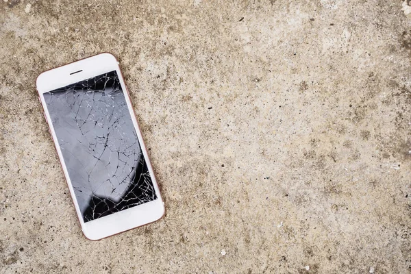 broken glass of mobile phone screen on concrete floor background