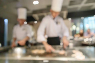 Lokanta mutfağında aşçı bulanık arka planda kalmış.