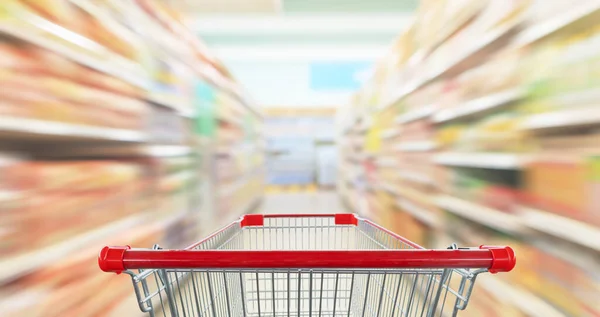 Empty shopping cart with abstract blur supermarket discount store aisle and product shelves interior defocused background