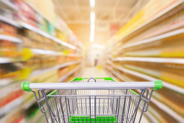 Market koridoru olan boş yeşil alışveriş arabası baharat ve sebze yağı şişeleri, ürün rafları iç taraf bulanık arka plan.