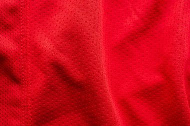 Kırmızı kumaşlı spor giyimli futbol forması, hava ağı desenli.