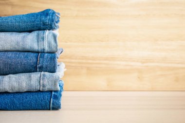 Ahşap arka planda kot pantolon yığını