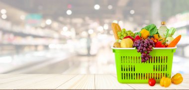 Tahta masanın üzerinde meyve ve sebzelerle dolu alışveriş sepeti. Süpermarket bakkalı. Bokeh Light ile bulanık arka plan.