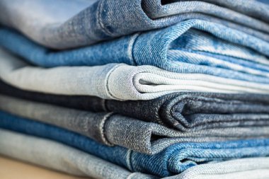 Ahşap arka planda kot pantolon yığını