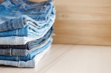 Ahşap arka planda kot pantolon yığını