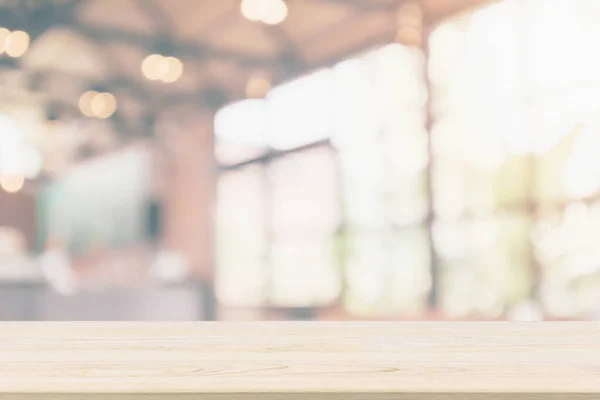 Empty wooden table top with cafe restaurant or coffee shop window interior abstract blur defocused with bokeh light background for montage product display