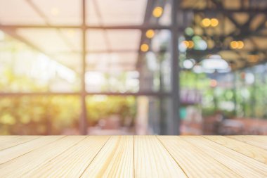 Boş ahşap masa üstü soyut bulanık kahve dükkanı ya da kafeterya arka planında montaj ürünü görüntüleme için bokeh ışığı olan