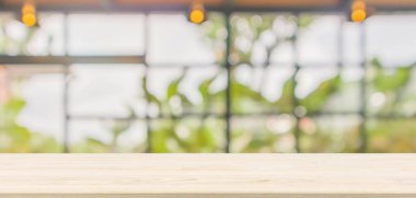 Boş ahşap masa üstü soyut bulanık kahve dükkanı ya da kafeterya arka planında montaj ürünü görüntüleme için bokeh ışığı olan