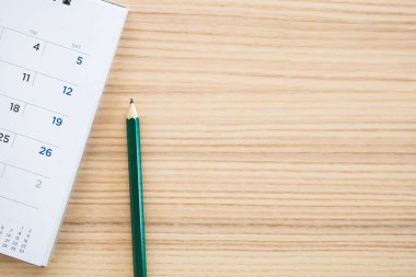 Ahşap masa zemininde kalem bulunan takvim sayfası