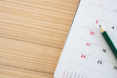 Ahşap masa zemininde kalem bulunan takvim sayfası
