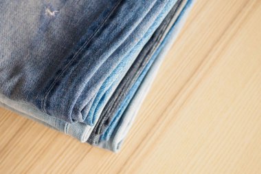 Ahşap arka planda kot pantolon yığını
