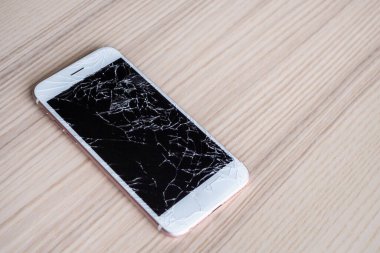 Ahşap arka planda kırılmış cep telefonu ekranı