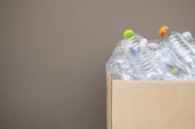 Kahverengi çöp kutusundaki plastik şişeler