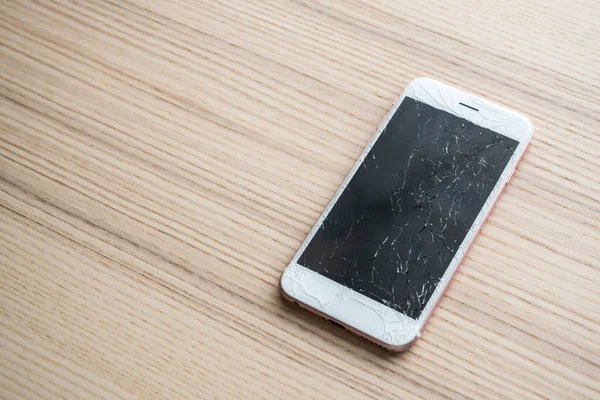 broken glass of mobile phone screen on wooden background
