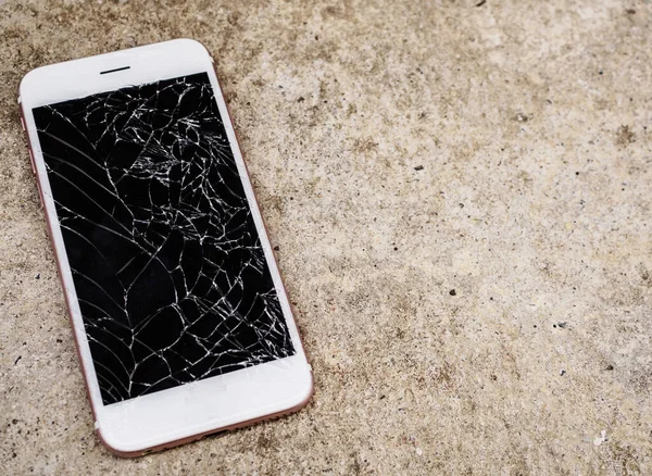broken glass of mobile phone screen on concrete floor background
