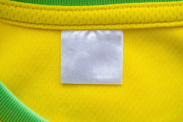 White blank textile clothes label on yellow sport clothing fabric jersey texture