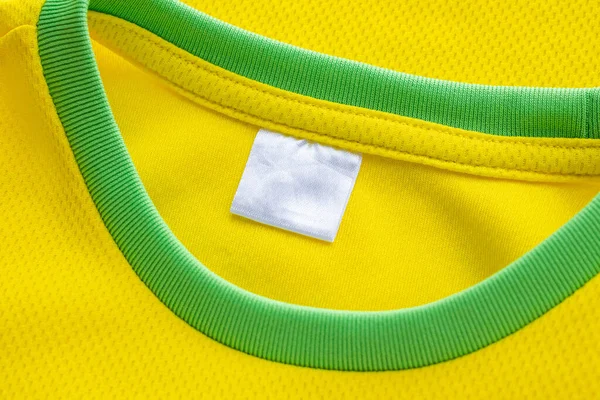 White blank textile clothes label on yellow sport clothing fabric jersey texture