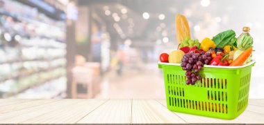 Tahta masanın üzerinde meyve ve sebzelerle dolu alışveriş sepeti. Süpermarket bakkalı. Bokeh Light ile bulanık arka plan.