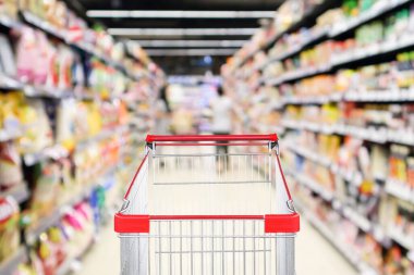 Soyut bulanık süpermarket indirim mağazası koridoru ve ürün rafları olan boş alışveriş arabası.