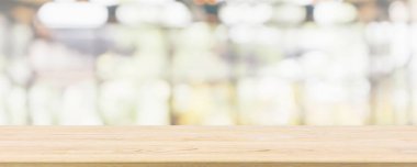 Kafe restoranı ya da kahve dükkanı penceresi olan boş ahşap masa üstü ya da montaj ürün gösterimi için bokeh ışığı arka planına odaklanmış soyut bulanıklık.